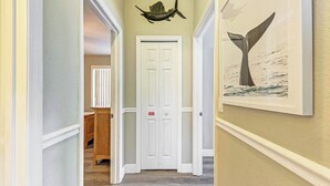 A hallway with a white door, a framed whale tail artwork, and a fish decoration on the wall. - Anna Maria Island Duplex: Pool, Kitchen, Sun Deck (Holmes Beach)