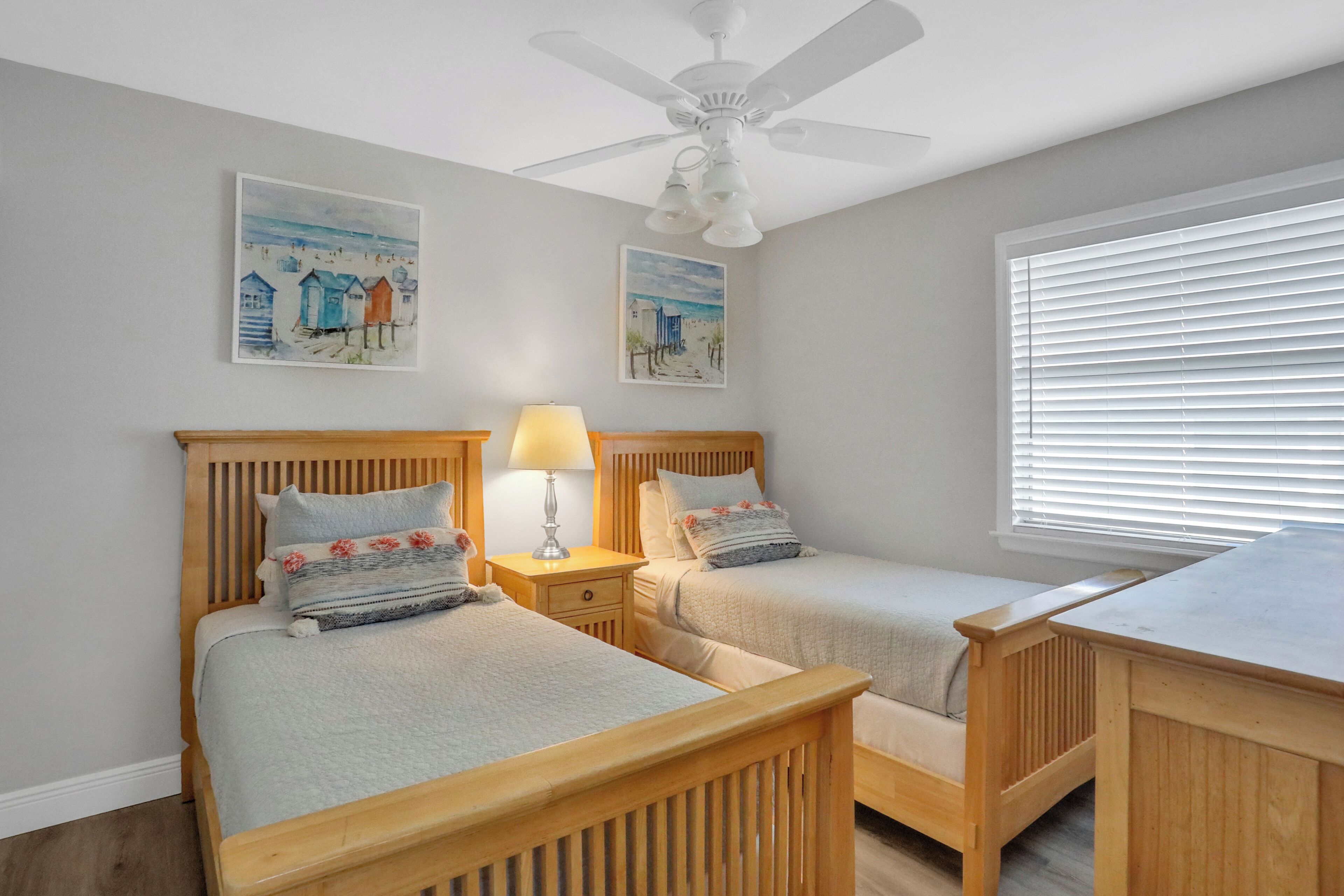 A bedroom with two wooden beds, a ceiling fan, and artwork on the walls.