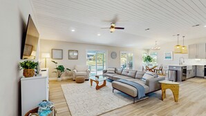 A spacious living area with a sofa, coffee table, and a television. There is a kitchen area with a dining table and chairs. - Swim Spa + Dock! Boater's Retreat on Marco Island (Marco Island)