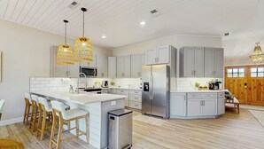 A modern kitchen with a central island, bar stools, stainless steel appliances, and pendant lighting. - Swim Spa + Dock! Boater's Retreat on Marco Island (Marco Island)