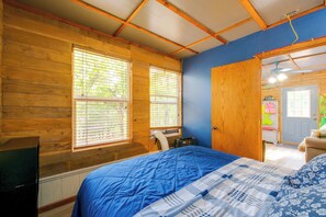 A bedroom with wooden walls, a blue bedspread, and a window with blinds. - Relax at 'The Cove' Waterfront Getaway (Eagle Rock)
