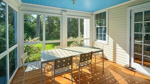 A covered patio with a table and chairs, large windows, and a view of greenery. - Close to Copake Lake! 4-Season Escape w/ Sauna (Copake)
