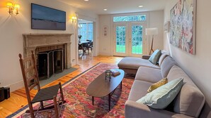 A living room with a fireplace, a sofa, a rocking chair, and a colorful rug. - Close to Copake Lake! 4-Season Escape w/ Sauna (Copake)