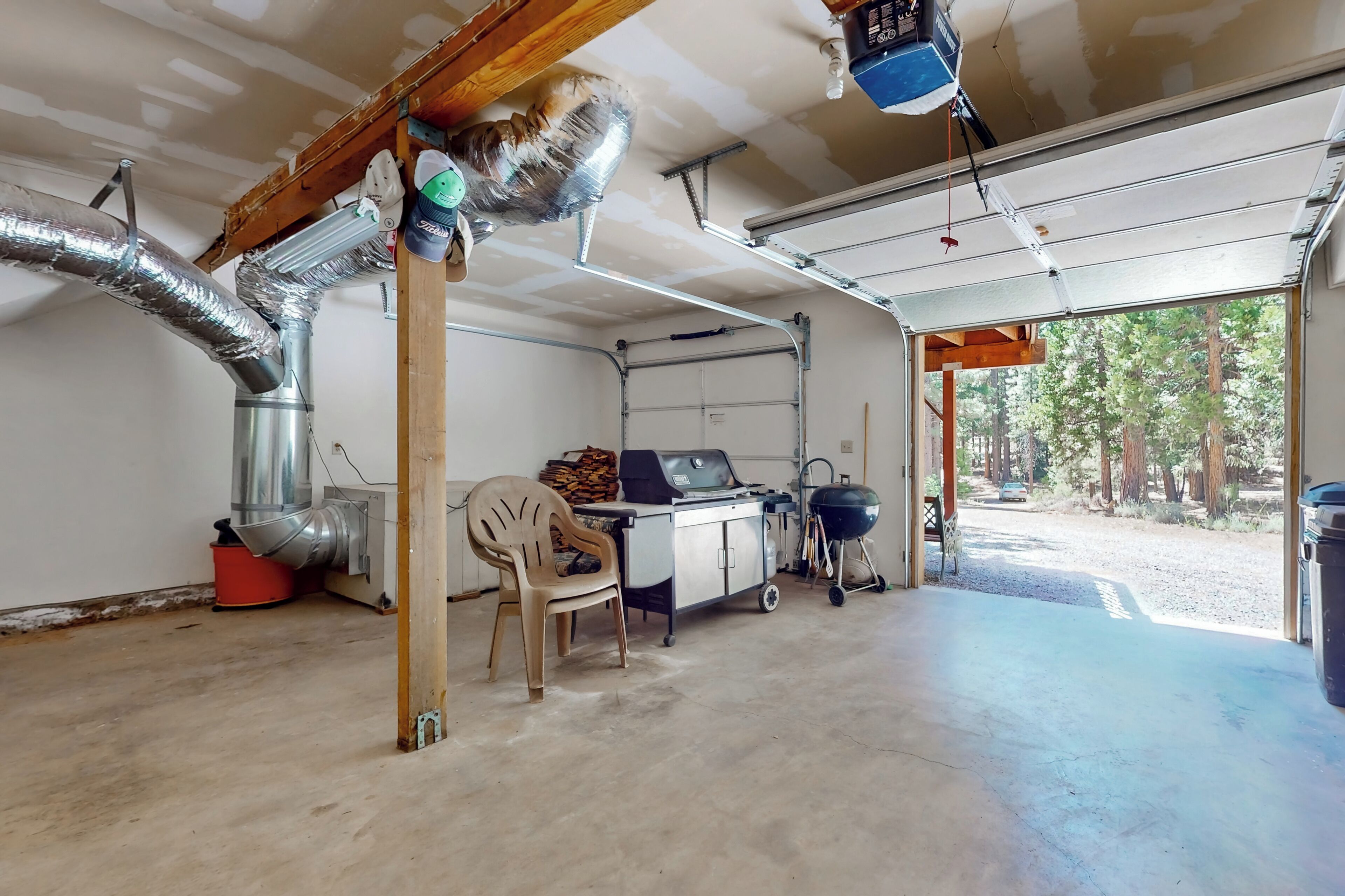 A garage with a workbench, ductwork, and a chair.