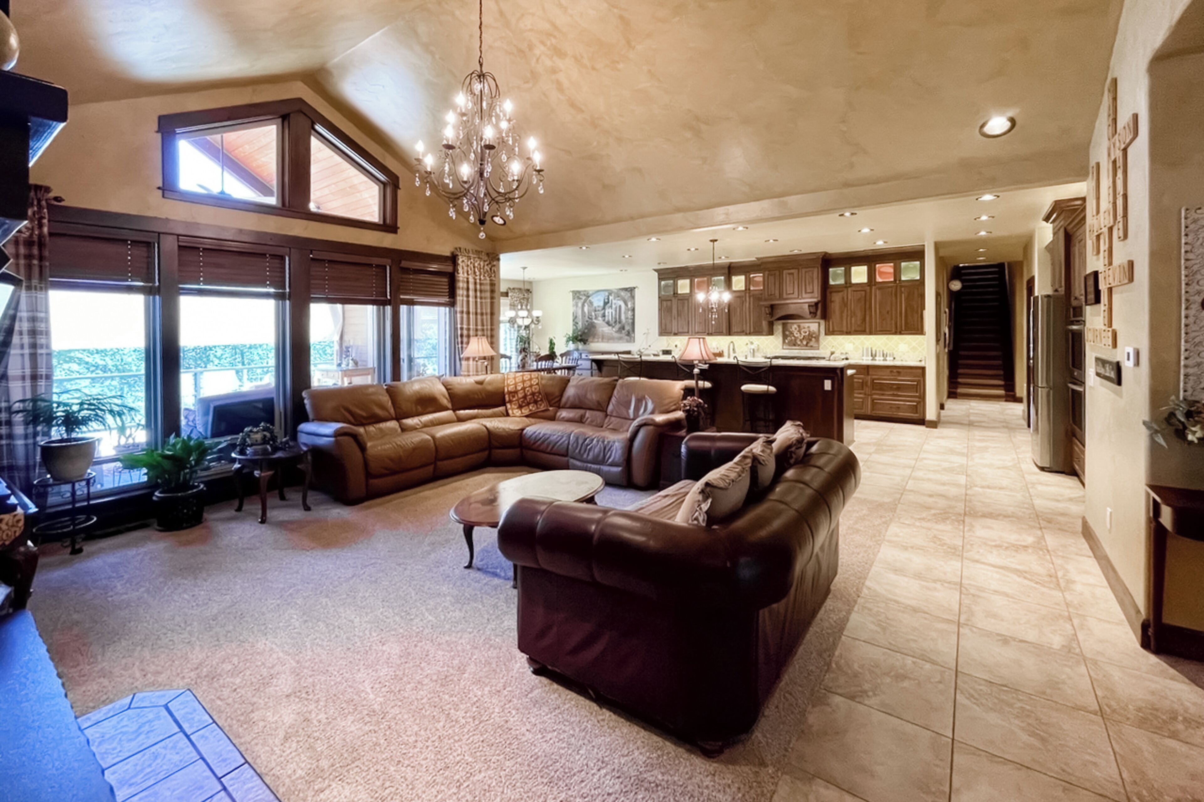 A spacious living room with a large sectional sofa, a coffee table, and a chandelier.