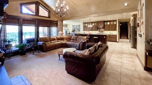 A spacious living room with a large sectional sofa, a coffee table, and a chandelier. - Angler's Oasis! Group-Friendly Deschutes River Gem (Bend)