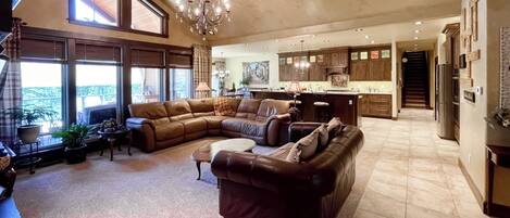 A spacious living room with a large sectional sofa, a coffee table, and a chandelier.