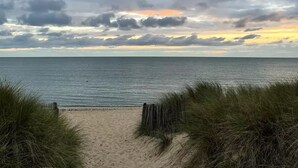 A beach with a sandy path leading to the water, surrounded by grass. - Mimosa 2 bedrooms 33m² + TV 4 persons (ST PIERRE D OLERON)