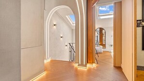 Un interior modern amb sòl de fusta, unes escales i un fanal.
