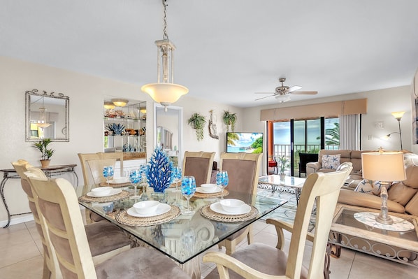 Un coin repas avec une table en verre, des chaises de couleur beige et un ventilateur de plafond.