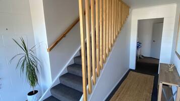 A staircase with wooden handrails, carpeted steps, and a small table with a plant.