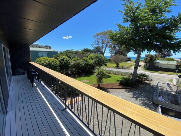A balcony with a view of a residential area, including a road, trees, and a building with a green roof.