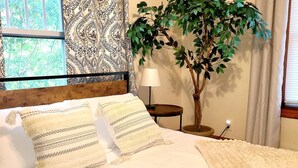 A neatly made bed with patterned pillows, a bedside lamp, and a small table. - Quiet Downtown Apt w/ Fireplace (Waterville)