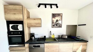 A compact kitchen with wooden cabinetry, a built-in microwave, a coffee machine, and a dishwasher.