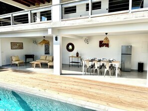Un espacio exterior moderno con piscina, asientos y comedor.