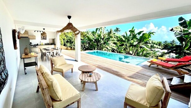 A modern outdoor living area with a pool, lounge chairs, and a dining setup.