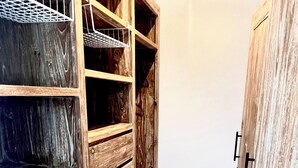 A wooden storage unit with multiple shelves and drawers, a metal rack, and a door with a handle.