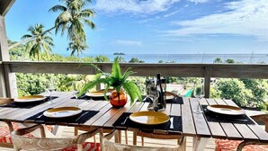 An outdoor dining area with a view of the ocean and palm trees.