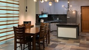 A modern kitchen with a dining area, featuring a central island, pendant lighting, and a built-in stove. - Ranchotel Guesthouse in Villasis (Villasis)