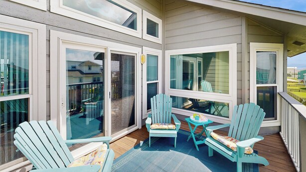 A covered outdoor area with a wooden deck, multiple Adirondack chairs, and a small table. - Walk to the Sand! Ocean-View Galveston Townhome (Galveston)
