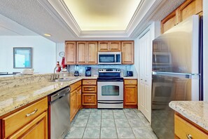 A kitchen with wooden cabinets, a stainless steel refrigerator, a microwave, an oven, and a dishwasher. - Gulf Views, Resort Perks: Suntide III - Unit 703 (South Padre Island)