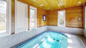 Ein Spa-Raum mit Holzbalkendecke, einem kleinen Pool und großen Fenstern.