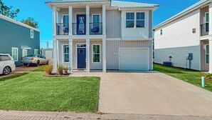 A two-story residential building with a garage, a front lawn, and a clear blue sky. - Walk to Eats! Family Hideaway 16 Mi to PCB (Panama City)