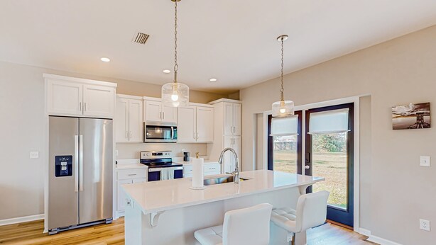 A modern kitchen with white cabinets, stainless steel appliances, and a central island with bar stools. - Walk to Eats! Family Hideaway 16 Mi to PCB (Panama City)