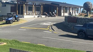 A building with a covered entrance, a parking area, and a sign indicating a golf club. - Family Beach House - Prime Location (Riversdale Beach)