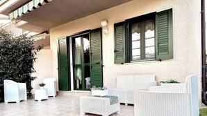 Un'area patio con mobili in vimini bianco, tra cui un divano e due poltrone, e un tavolino.