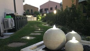 Un giardino con tre elementi acquatici sferici e un vialetto.