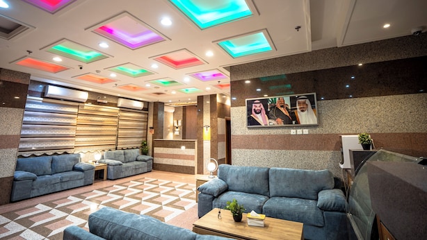 A lobby with sofas, a reception desk, and a ceiling with illuminated panels. - MG Crown Hotel 4 (Madinah)