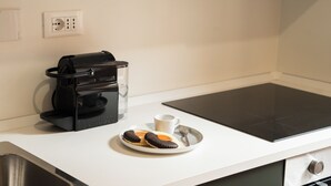Uma bancada de cozinha com uma cafeteira, um prato com biscoitos e uma xícara.