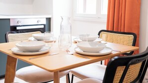 Uma mesa de jantar posta com pratos brancos, tigelas e um jarro de vidro transparente.