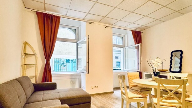 Un salon meublé comprenant un canapé, une table à manger, des chaises et une vue par les fenêtres.