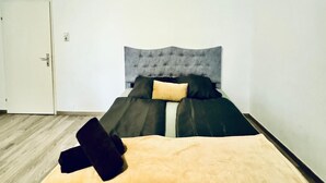 Une pièce avec un lit, une porte et un interrupteur sur le mur.