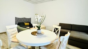 Un coin repas avec une table ronde, des chaises blanches et une plante en pot.