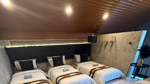 Een moderne slaapkamer met drie bedden, een zwart pluizig vloerkleed en een zwarte stoel.