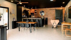 Een moderne bar met een bakstenen muur, barstoelen en plafondventilatoren.