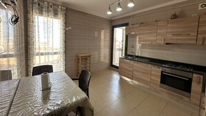 Une cuisine moderne avec des meubles en bois, une cuisinière à gaz et un coin repas comprenant une table et des chaises.