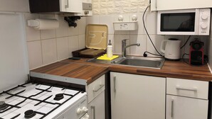 Ett kök med en gasspis, en mikrovågsugn, ett handfat och en kaffebryggare.