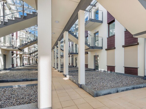 Ein modernes Gebäude mit mehreren Etagen, großen Glasfenstern und einem zentralen, offenen Bereich mit einem Kiesweg.