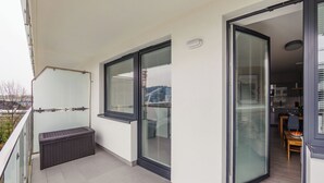 Un balcon avec un banc, de grandes fenêtres et une vue sur l’extérieur.