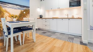 Une cuisine moderne avec des meubles blancs, un four à micro-ondes et un coin repas comprenant une table et des chaises.