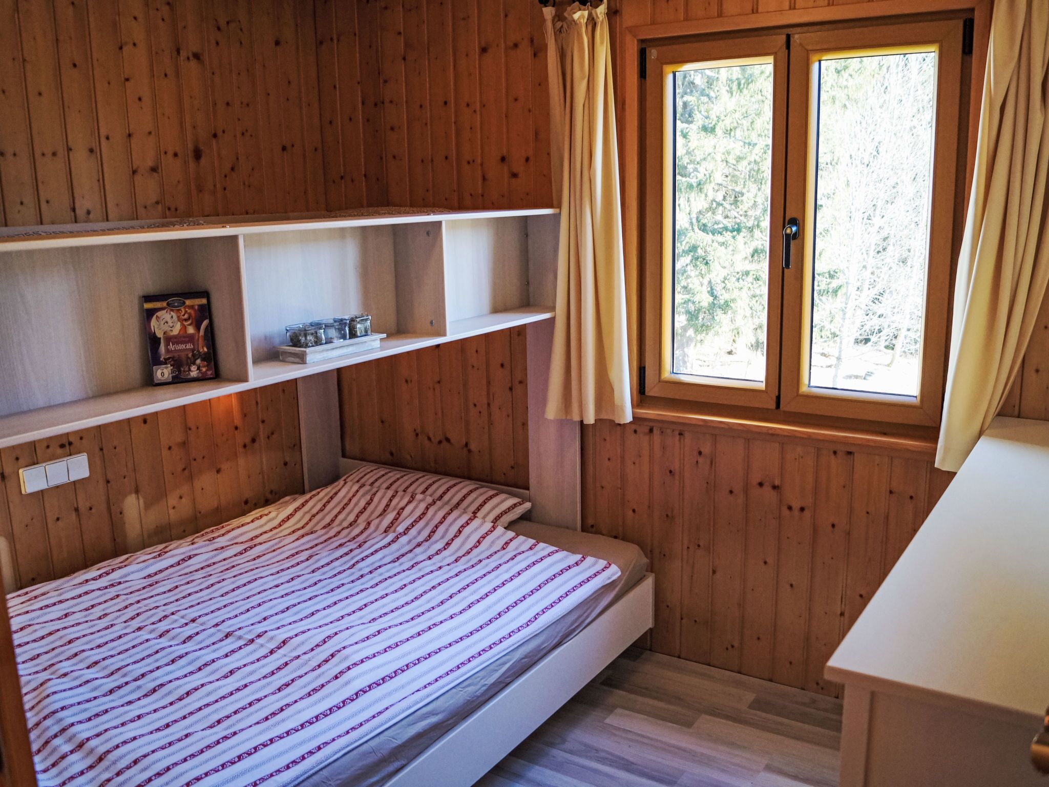 Ein Holzhütten-Zimmer mit Bett, Regalen und einem Fenster.