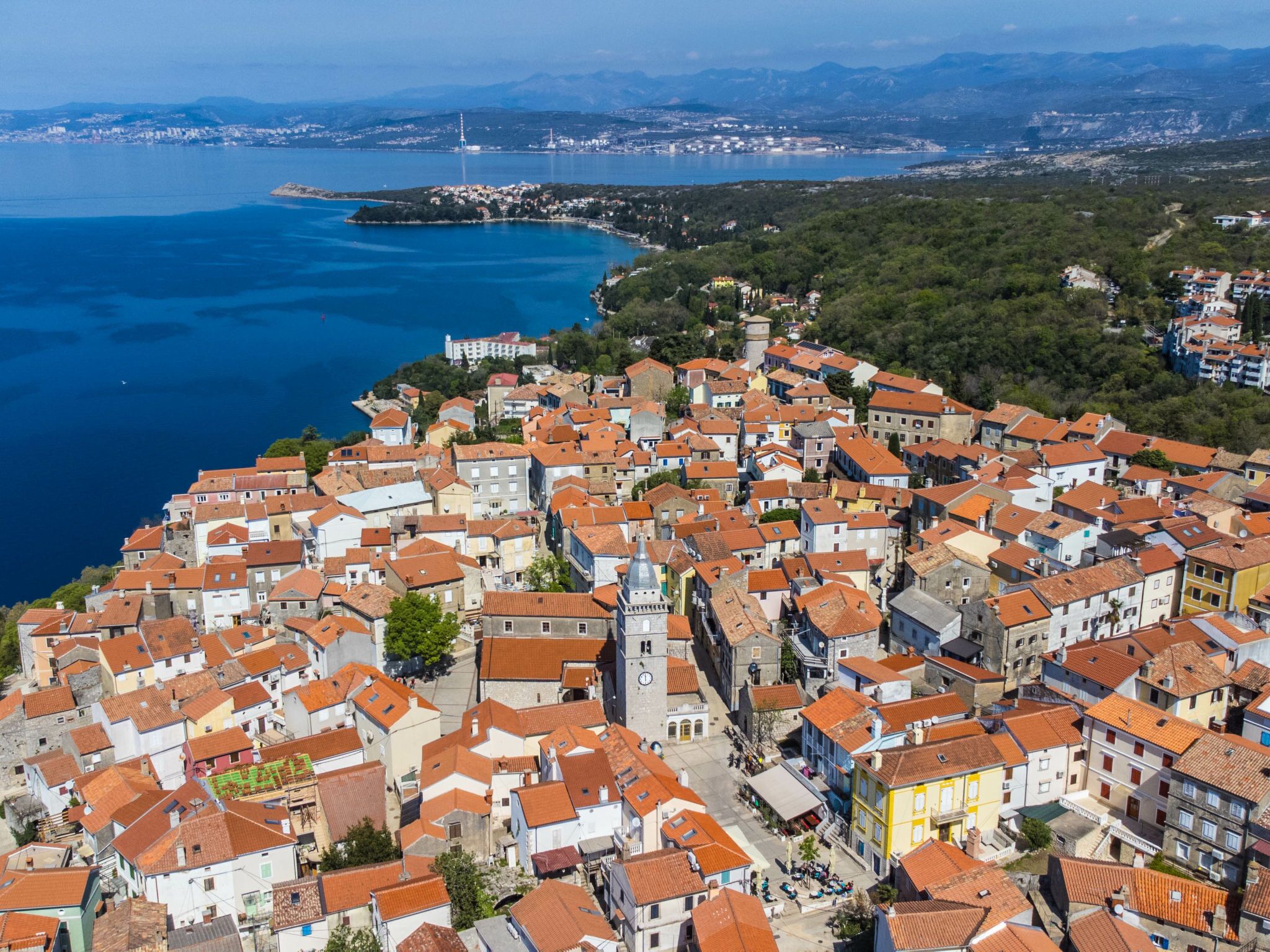 A coastal town with tightly packed buildings, a prominent tower, and a view of the sea.