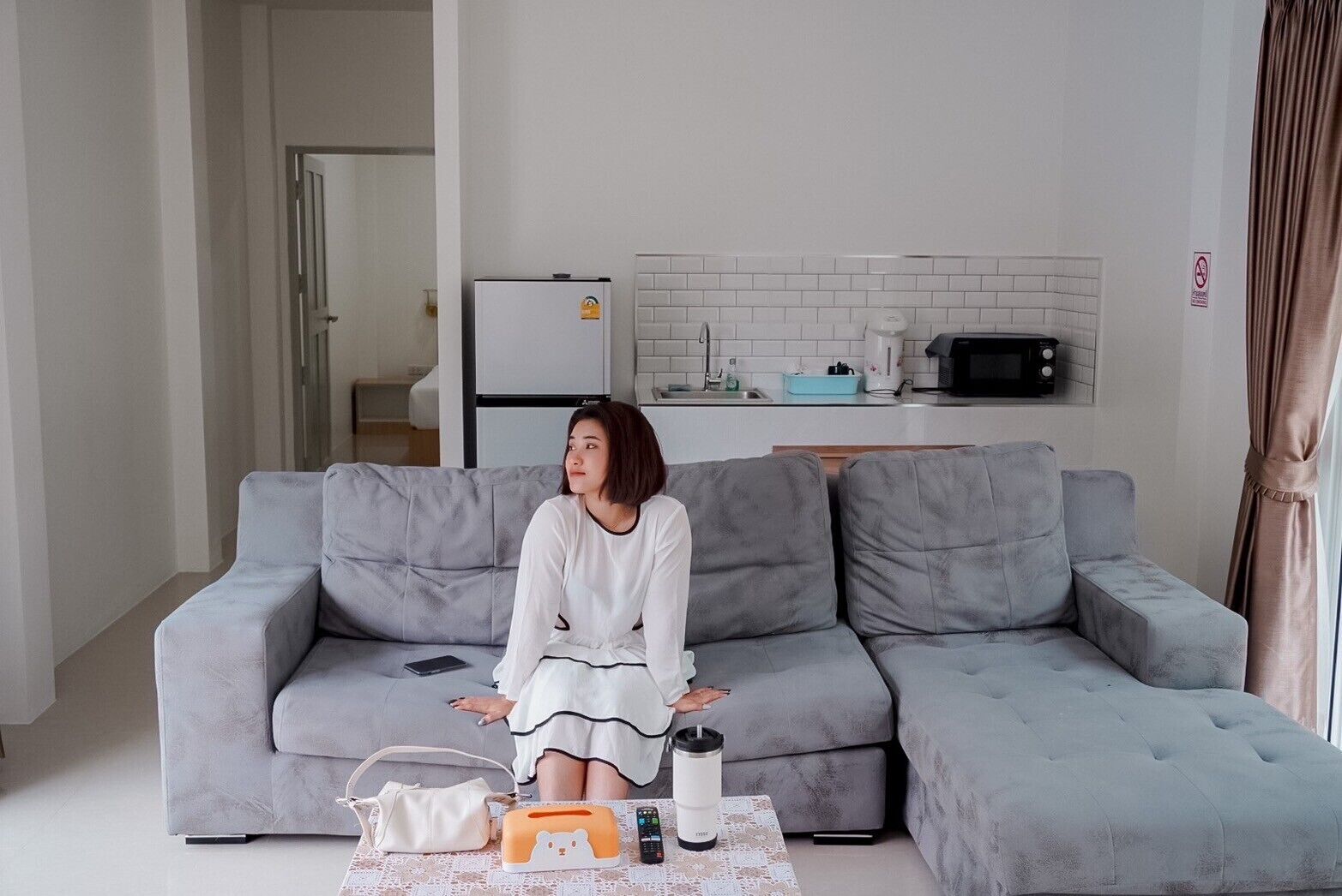 A living room with a grey sofa, a coffee table with a laptop, a remote control, and a water bottle.