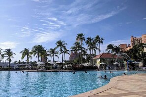 A swimming pool with palm trees and a hotel in the background.