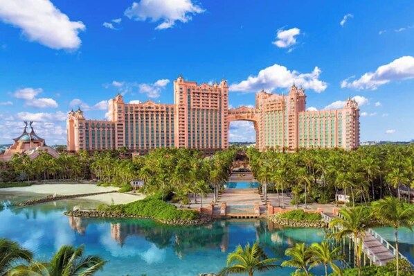 A large resort with multiple high-rise buildings, a central archway, and a pool area surrounded by palm trees.