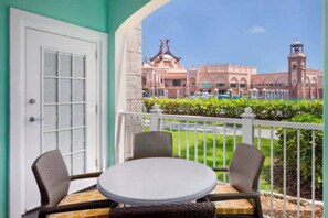 A balcony with wicker chairs and a table, overlooking a building with arched windows and a clock tower. - Harborside Resort - Two Bedroom Small - Full Resort Access (Paradise Island)